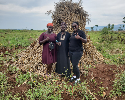 Ugandan maize farmer Namakoye Josephin standing in front of one of her maize heaps